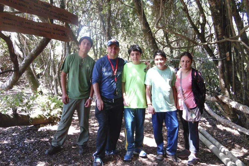 Niño deslizándose en línea de canopy entre vegetación verde